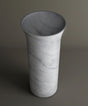 The TRAVERTABLE Carrara Marble Cylinder Pedestal Vanity Sink features a tall, cylindrical shape with a flared opening and subtle gray veining, evoking the timeless beauty of high-end marble bathroom sinks.