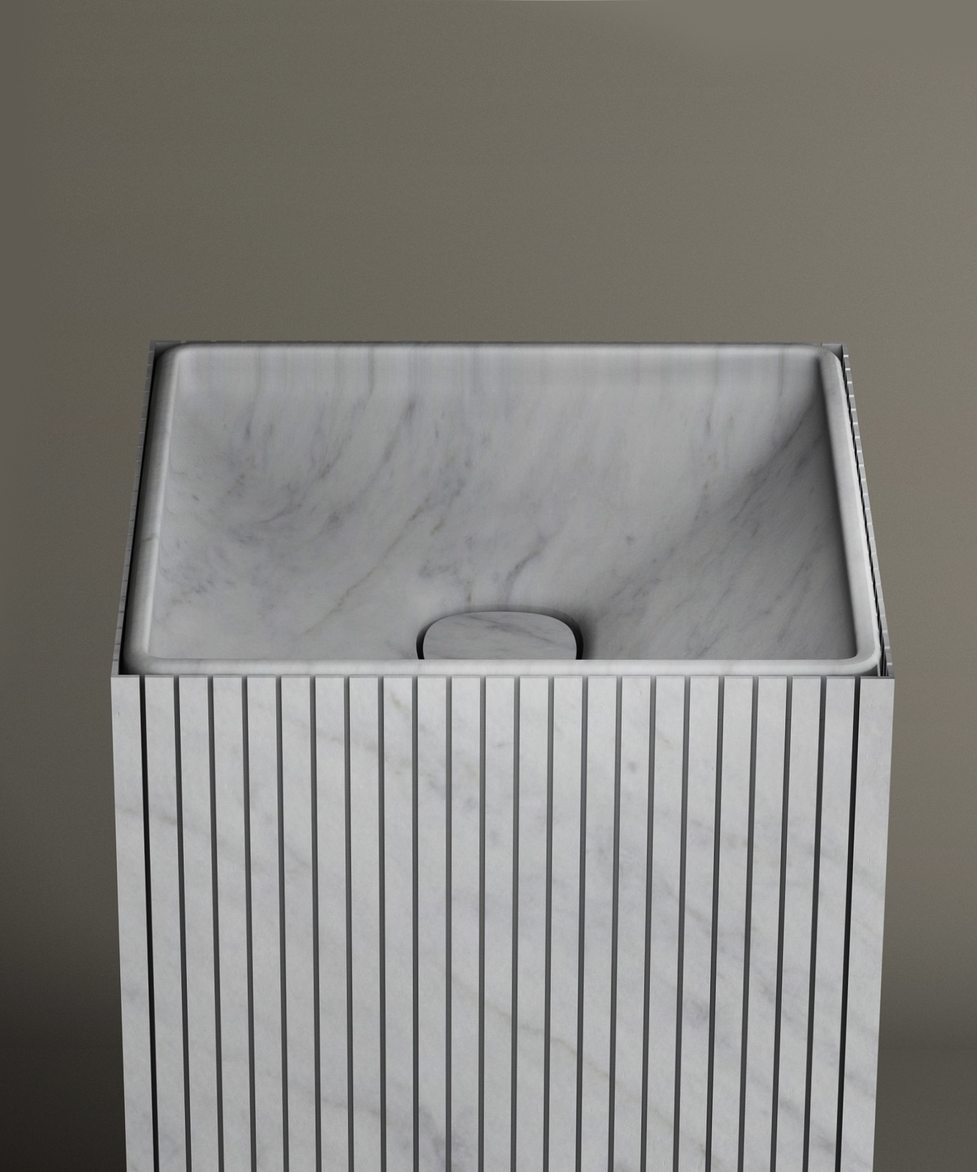 The TRAVERTABLE Carrara Square Fluted Marble Pedestal Vanity Sink features vertical grooves, a smooth angled basin, and a minimalist design—ideal for contemporary bathrooms with neutral backgrounds.