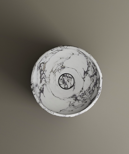 The TRAVERTABLE Calacatta Round Marble Pedestal Vanity Sink features elegant gray veining and a centered drain, showcasing Italian craftsmanship. Viewed from above against a taupe background, it enhances any bathroom space.