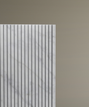 Only the left half of the TRAVERTABLE Carrara Square Fluted Marble Pedestal Vanity Sink, featuring vertical grooves in white marble and designed for contemporary bathrooms, is visible against a plain light brown background.