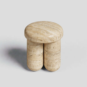 The Travertable Travertine Elegance Accent Table, a minimalist stool with a smooth, round top and two cylindrical legs, is crafted from beige travertine stone and set against a plain grey background.