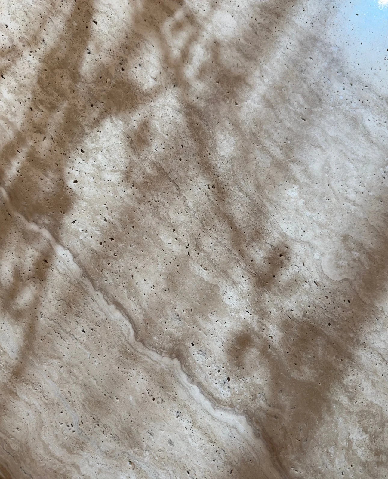 Elegant travertine coffee table with organic edges and a sculptural base, featuring rich natural stone patterns.